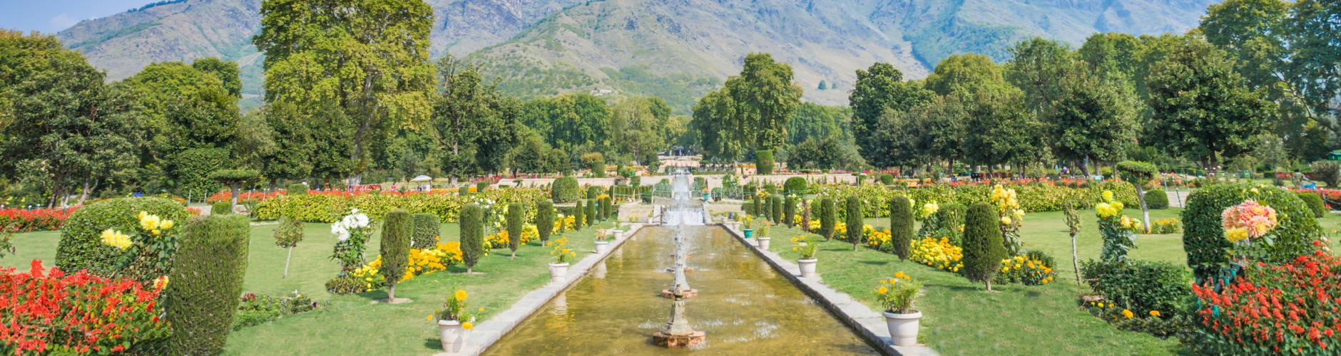 An open garden with fountain in the centre and mountains surrounded