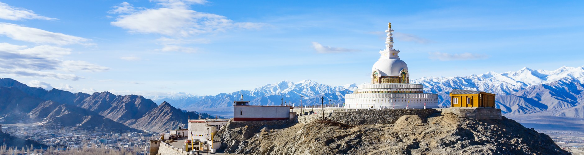 A white colour building on the top of a mountain with other mountains surrounded